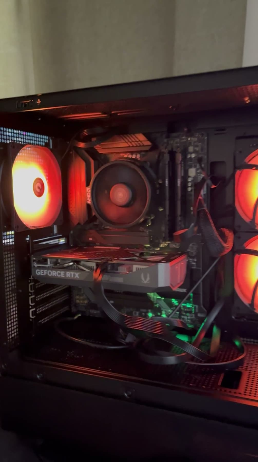 The inside of a finished build lit in red, showing the graphics card, cooler and cable routing.