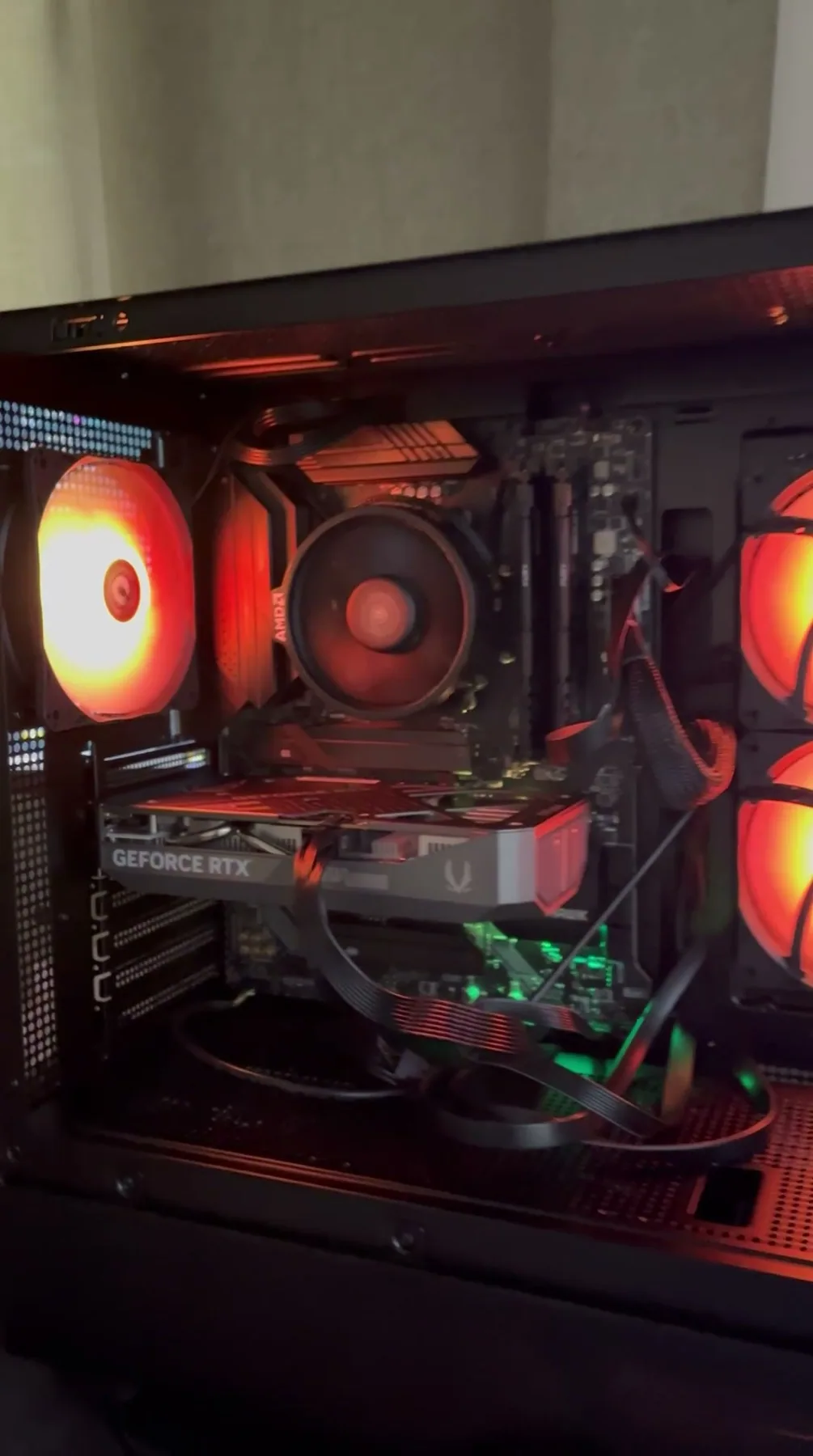 The inside of a finished build lit in red, showing the graphics card, cooler and cable routing.